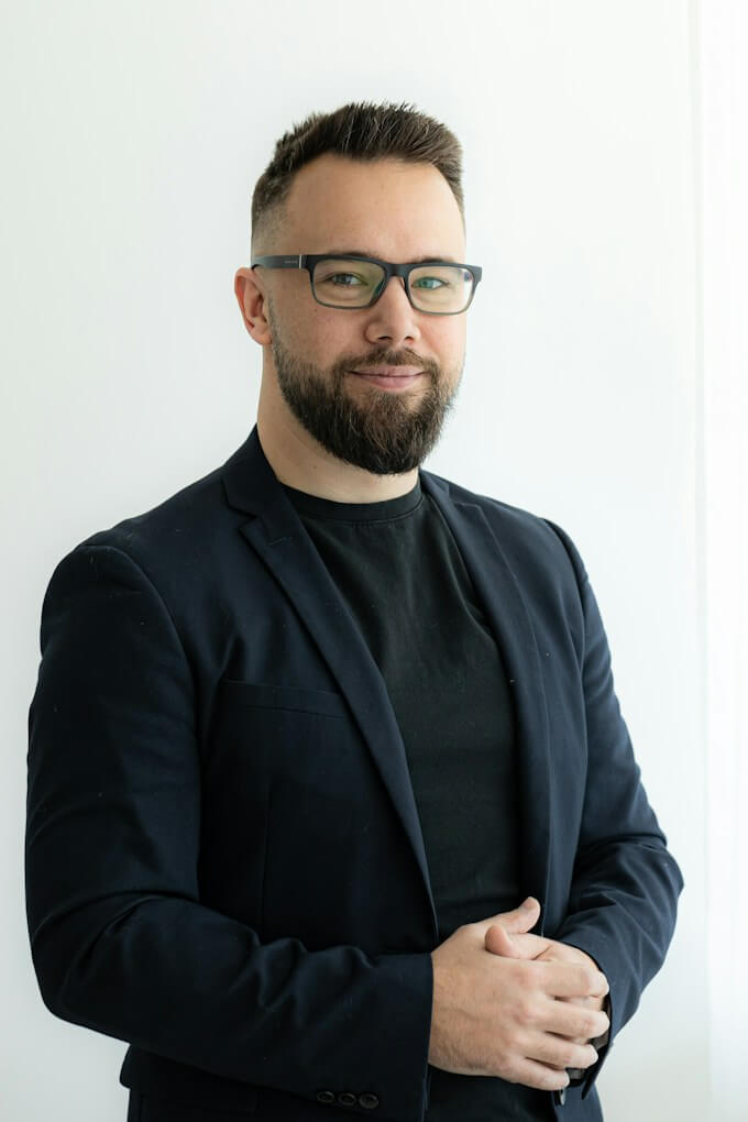 Man med glasögon och skägg i svart kavaj, företagsporträtt
