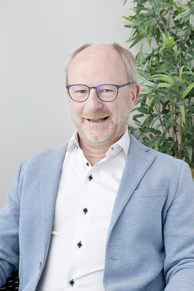 Leende äldre man i ljusblå kavaj och vit skjorta, företagsporträtt